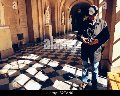 Middle aged man using old vintage film camera inside Palace of Versailles Stock Photo