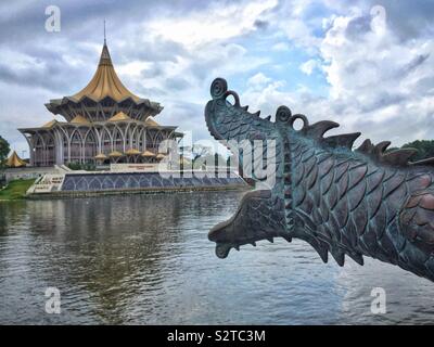 One of a pair of cannons styled as Chinese dragons overlooking the Sarawak River, with the State Legislative Assembly Building, Kuching Waterfront, Sarawak, Malaysia Stock Photo