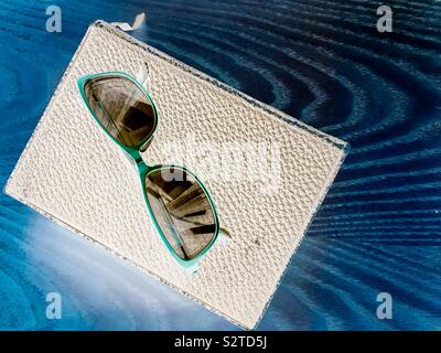 Flat lay image of a pair of reading glasses and an old book resting on a wooden table Stock Photo