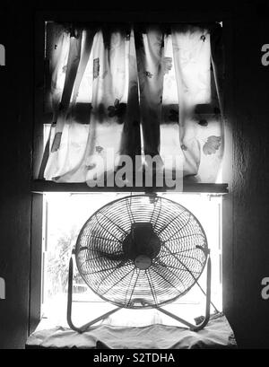 Floor fan sitting on window on a hot and sunny day. Stock Photo