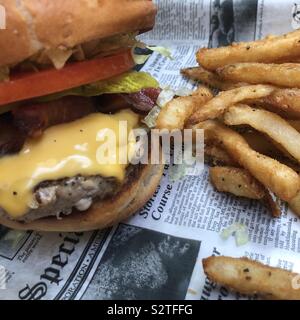A cheeseburger and French fries on a newsprint paper Stock Photo