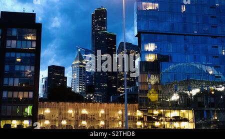 Downtown Seattle at dusk with reflections of stadium along with views of iconic Smith Tower and Columbia Center - the tallest building in the city. Stock Photo