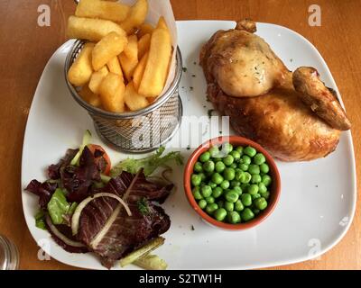 Chicken, chips, peas and salad on a white plate Stock Photo