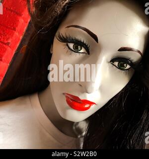 A closeup of a dark haired mannequin who has bright red lips Stock Photo