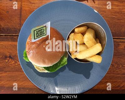 Vegan burger and chips on a blue plate, on a wooden table. Plant based food. Stock Photo