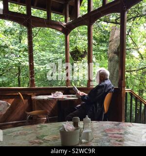 A senior man enjoys a book at Queen’s Wood Cafe, London Stock Photo