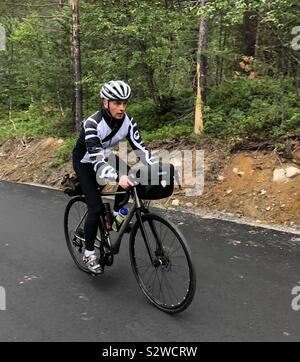 Male cyclist riding up steep hill in the Romsdal Valley, Norway Stock Photo