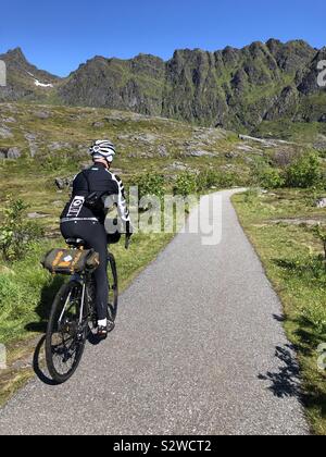 Male cyclist riding through the Lofoten Islands, Norway. Stock Photo