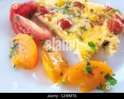 Close view on white plate with omelette and sliced yellow and red tomatoes Stock Photo