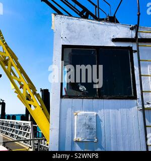 A pigeon sitting inside the cab of an old disused jetty crane on the end of Ryde Pier at Ryde on the Isle of Wight Stock Photo