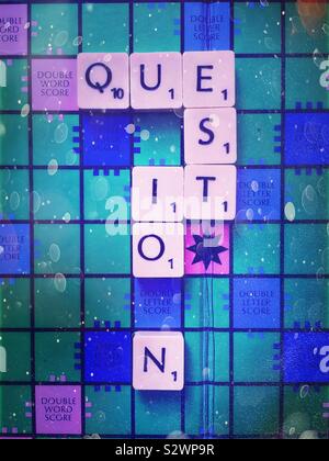 A Scrabble board with the word ‘question’ spelled out in the shape of a question mark, with rainy day appearance Stock Photo