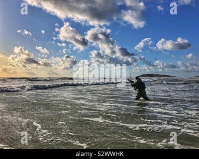 Angler casting into the surf at Llangennith beach , Gower, Swansea, South West Wales, August. Stock Photo