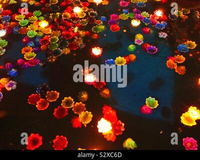 Colourful candles floating on the water at night on New Years Eve in a Bangkok Buddhist temple in Thailand Stock Photo
