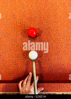 Woman playing pool on a red table Stock Photo