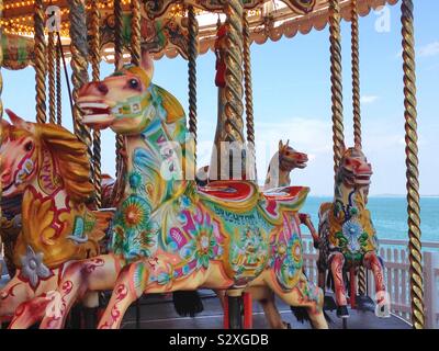 Carousel horse at the seaside on the pier at Brighton with the sea behind Stock Photo