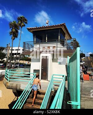 A woman walks up steps from the beach towards Manhattan Beach Pier, Manhattan Beach, California, United States Stock Photo