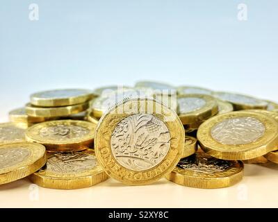 One pound coin on edge with pile of coins in the background Stock Photo