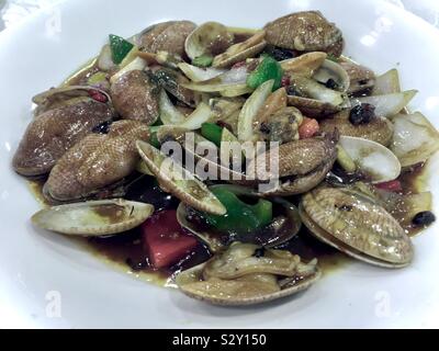 Plate of sautéed clams with black bean sauce, onions, garlic and peppers, Asian style. Kowloon, Hong Kong. Stock Photo