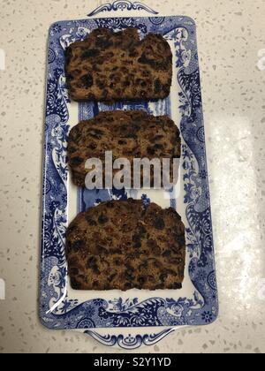 An overhead view of slices of Bara Brith made with goji berries on a blue and white sandwich plate. Stock Photo