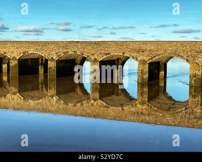 Arched bridge in early morning light reflected in still water Stock Photo
