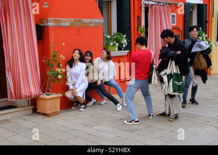 Asian tourist girls posing for pictures by a brightly coloured wall Stock Photo