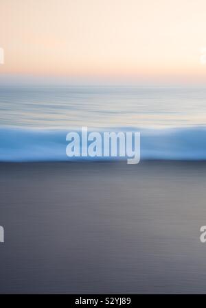 An ethereal water image of a wave in motion with blue creating a beautiful ocean nature background at sunset with copy space Stock Photo