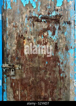 Old wooden door with shades of brown and blue peeling paint Stock Photo
