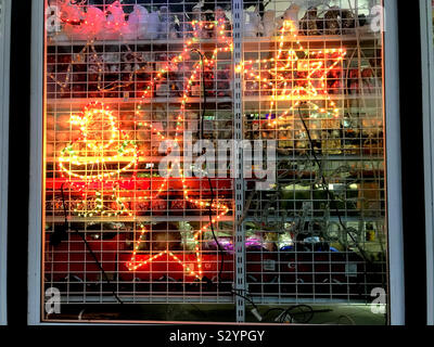 Xmas decoration lights in a shop window for sale behind a grille Stock Photo