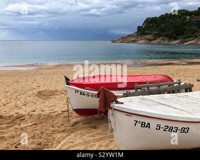 Two fishing boats moored side by side on the beach in Llafranc on a wet November day, Costa Brava, Spain. Stock Photo
