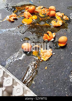 Close up of a dozen broken brown eggs on a sidewalk in New York City, USA Stock Photo