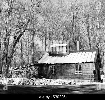 Black and white image of a small building in a snowy landscape near the road, Warren, Vermont, United States Stock Photo