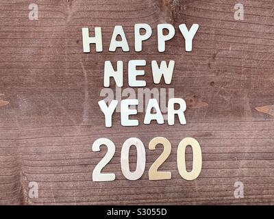 Happy New Year 2020 composed with wooden letters and numbers over a wooden board Stock Photo