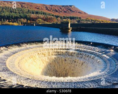 Ladybower reservoir bellmouth overflows or plugholes after heavy rain in November 2019 with autumn colours on hillside Bamford Derbyshire England UK GB Europe Stock Photo