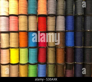 A closeup photo of many spools of colorful thread aligned in rows Stock Photo