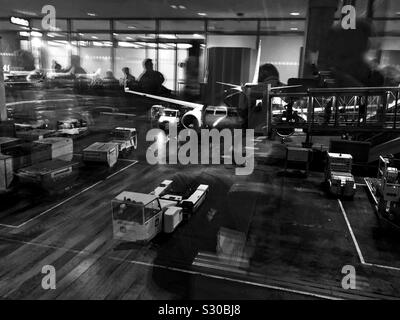 A single exposure showing the activity outside by the gate and the interior of the departure lounge reflected in the window at Oslo international airport. Stock Photo