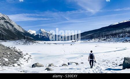 Young man walking with camera in hand in spectacular Medicine Lake in Canada’s Jasper National Park. Stock Photo