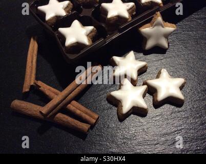 Cinnamon stars in plastic packaging and some cinnamon sticks Stock Photo