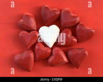 Different love, conceptual and creative composition with red wooden hearts around a white heart Stock Photo