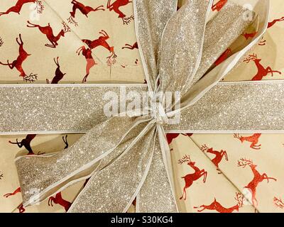 Gift wrapped box with reindeer motif and gold sparkly ribbon Stock Photo