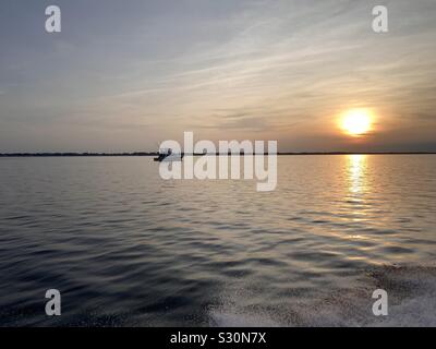 Sunset on the Gulf of Mexico with a boat going towards setting sun Stock Photo