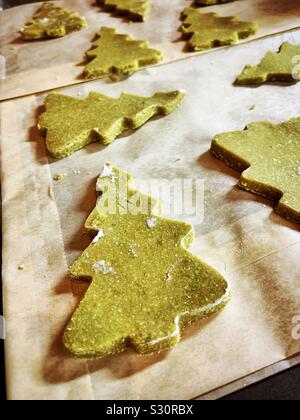 Green matcha Christmas tree cookies are placed on a baking sheet ready to go into the oven. Stock Photo