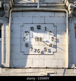 Old clock with shadows of numerals on stone building, Chatellerault, Vienne, France. Stock Photo