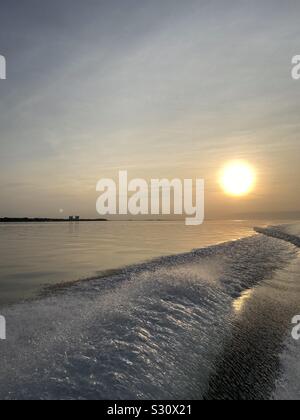 Sunset on Gulf of Mexico water with wake water from boat and reflections on water Stock Photo