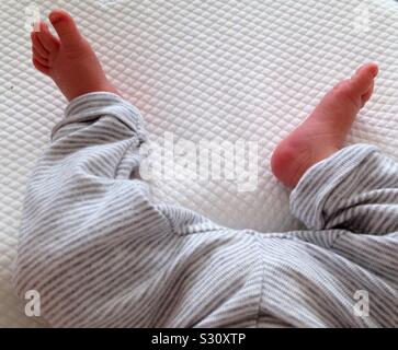Close up of a newborns feet and legs wearing a striped suit. Stock Photo