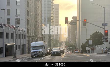 LOS ANGELES, CA, DEC 2019: traffic at lights on Olive Street, near Bunker Hill in Downtown. Late afternoon with cityscape falling off into golden haze Stock Photo
