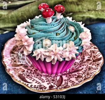 Cup Cake decorated with Blue and White Icing And Toadstools placed on a Saucer at The Mad Hatters Tea Party. Alice in the Palace at Christmas- Blenheim Palace 2019 Stock Photo
