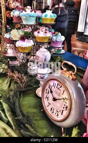 Alice in the Palace at Blenheim Palace Christmas 2019 - Mad Hatters tea Party table with a stand of cupcakes on it and a clock. Stock Photo