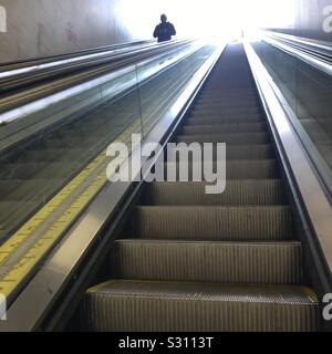 man moving down on escalator stairs Stock Photo