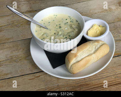 Cullen Skink traditional Scottish soup is shown, containing white fish, potatoes, onions, and milk. Bread and butter are served on the side. Stock Photo