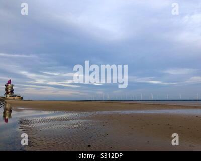 Redcar vertical pier reflected in pools left by the sea. A wind farm can be seen off shore. Stock Photo